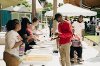 a group of people standing around a table with food